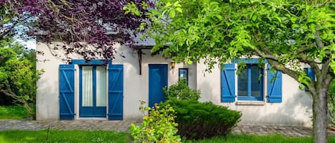 A building with blue shutters and a stone pathway leading to the entrance.