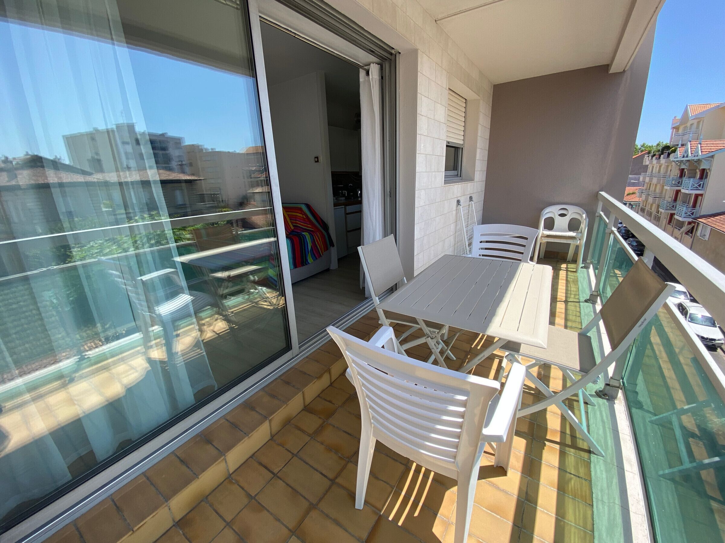 A balcony with a table and chairs, a sliding glass door, and a view of the cityscape.