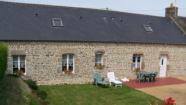 A stone building with a sloped roof, multiple windows, and a small patio area with outdoor seating. - Charming 2-Bedroom House with Garden, BBQ, and Fireplace in Vicq-sur-Mer (Vicq-sur-Mer)