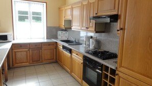 A kitchen with wooden cabinets, a microwave, a sink, a coffee maker, and a stove. - Charming 2-Bedroom House with Garden, BBQ, and Fireplace in Vicq-sur-Mer (Vicq-sur-Mer)