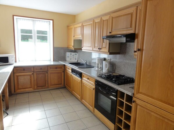 A kitchen with wooden cabinets, a microwave, a sink, a coffee maker, and a stove.