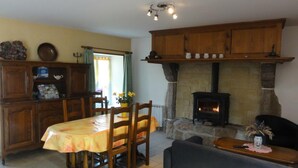 A cozy living room with a fireplace, wooden furniture, and a dining area with a table and chairs. - Charming 2-Bedroom House with Garden, BBQ, and Fireplace in Vicq-sur-Mer (Vicq-sur-Mer)