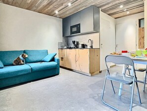 Un espacio habitable compacto con kitchenette, un sofá y una zona de comedor.