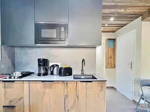 Cocina compacta equipada con microondas, cafetera, tostadora y lavabo.