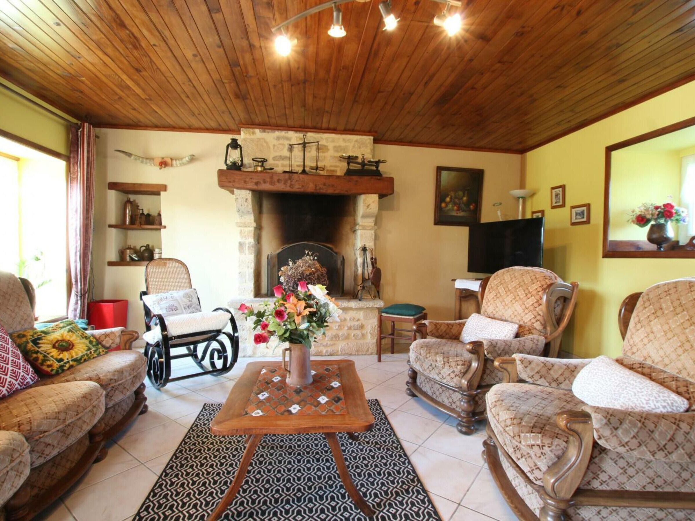 Un accogliente soggiorno con camino, soffitto in legno e arredamento decorato.