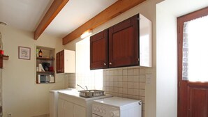 Eine kleine Küche mit weißen Geräten, Holzschränken und einer gefliesten Spritzschutzwand.