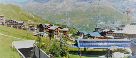 A mountain resort with chalet-style buildings, a ski lift, and a modern glass structure.