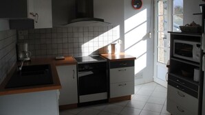 Una cocina con armarios blancos, estufa, lavavajillas y microondas.
