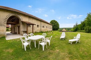 Ein rustikales Gebäude mit einer Terrasse, komplett mit Tisch und Stühlen.