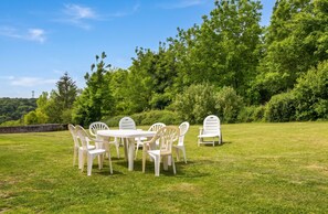 An outdoor seating area with a table and chairs, surrounded by lush greenery and trees. - Homerez - House near Monthenault (Monthenault)
