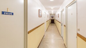 Un couloir avec des portes portant les inscriptions « 1 PRIVÉ » et « 3 », et des tableaux encadrés accrochés aux murs.