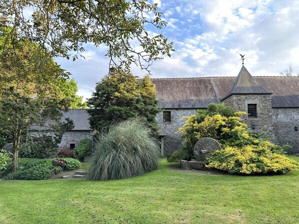 Un bâtiment en pierre doté d’un toit conique et d’une girouette.
