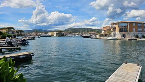Un port de plaisance avec des bateaux amarrés, une jetée en bois et des bâtiments dotés de balcons.