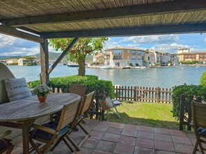 Una terraza con mesa y sillas, vistas a un lago y edificios al fondo.
