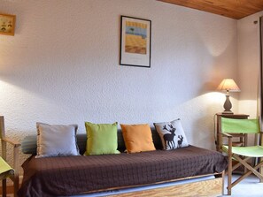 Um quarto aconchegante com uma cama, um quadro na parede e uma luminária em uma mesa lateral.