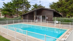 A rectangular swimming pool with a white metal fence, surrounded by a gravel area and grass. - Beachfront Villa with Garden & Pool, 200m from Seignosse Beach (Seignosse)