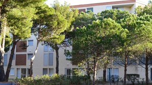 Un edificio de varios pisos con un estilo arquitectónico moderno, que presenta una combinación de balcones y ventanas.