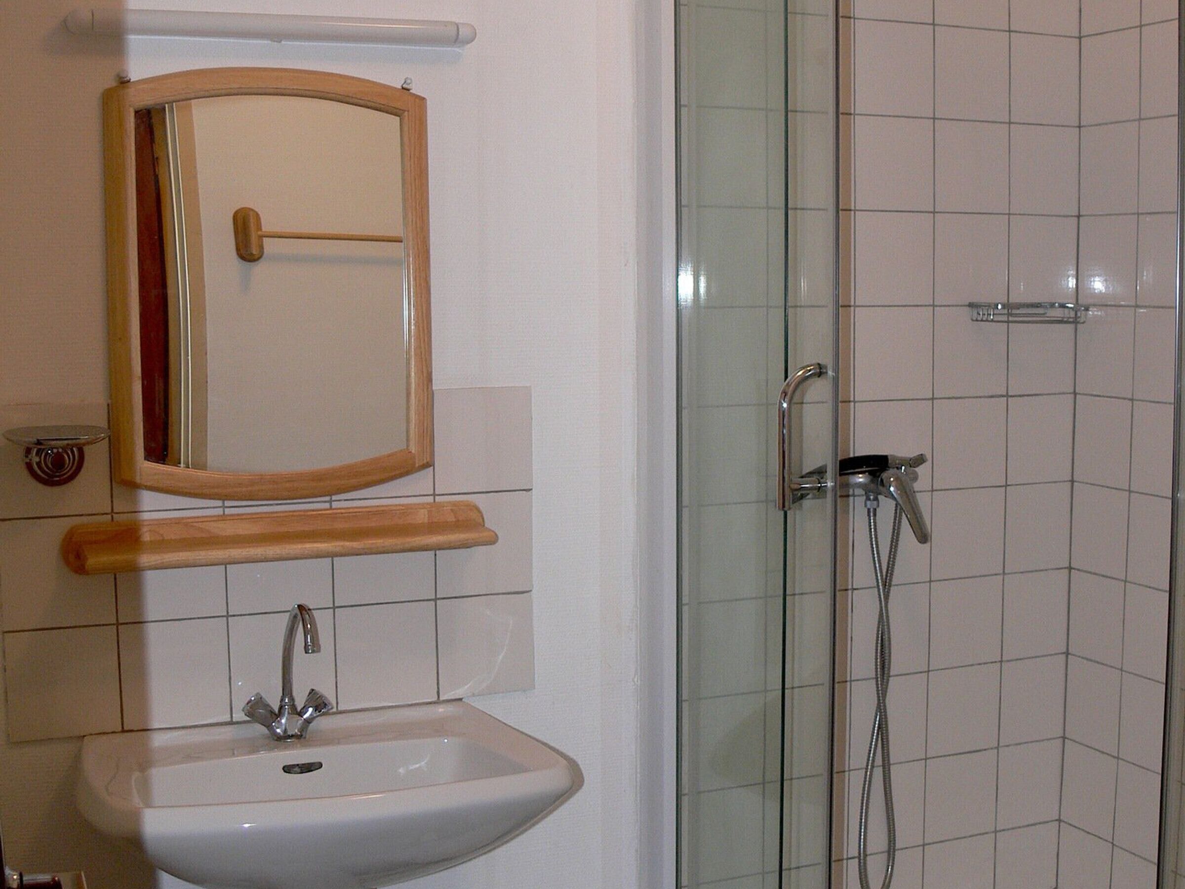 Een badkamer met een wastafel, spiegel en douche.