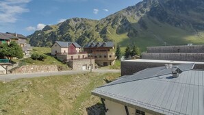 A mountain village with traditional houses, a stone wall, and a view of the mountains.