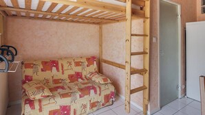A small room with a bunk bed, a sofa, and a door.