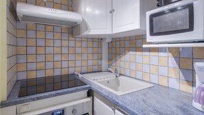 A compact kitchen with a microwave, stove, and sink.
