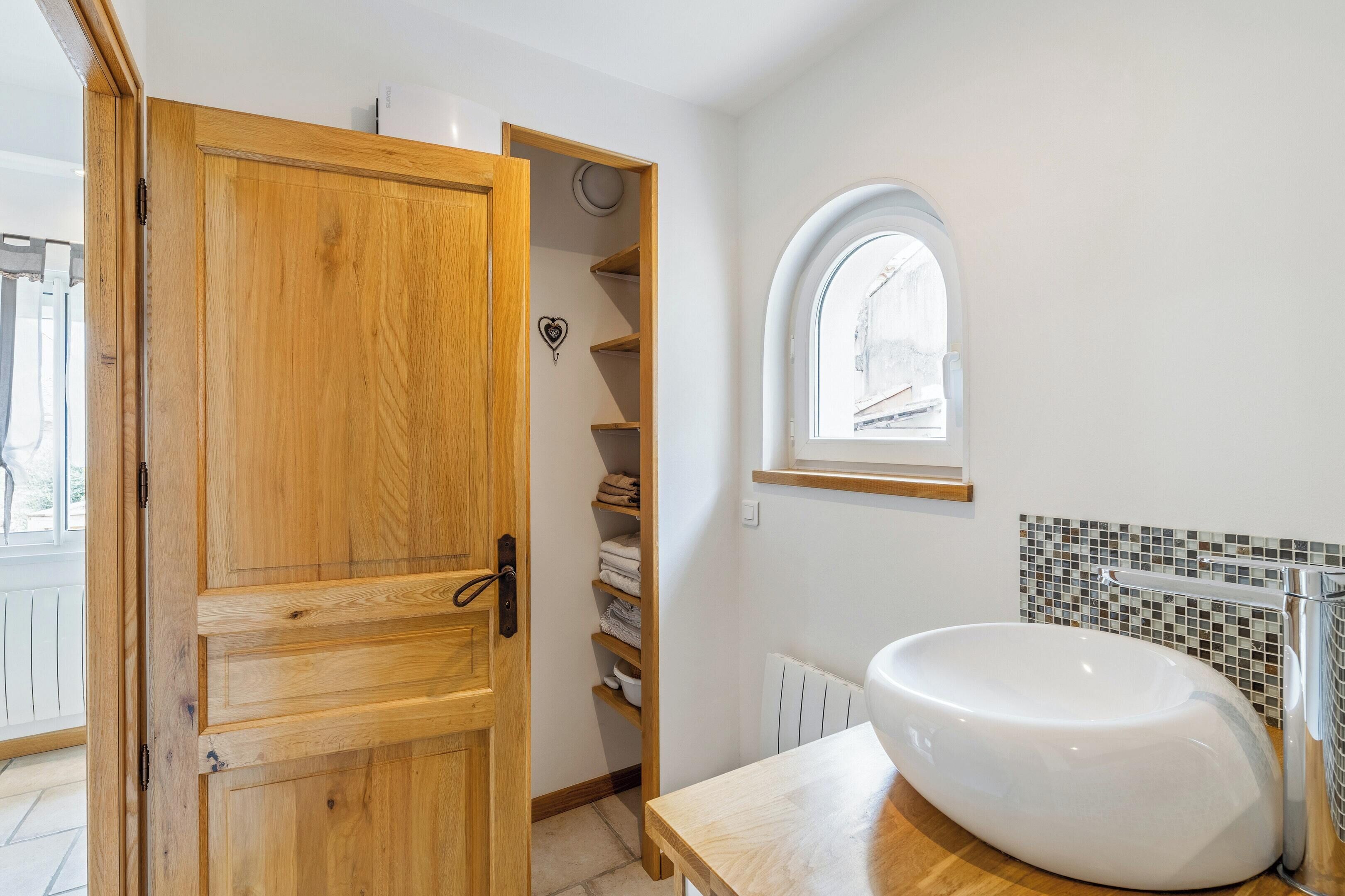 A bathroom with a wooden door, a white sink, and a tiled backsplash.