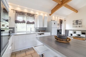 A modern kitchen with white cabinetry, a built-in oven, and a large island with a sink.