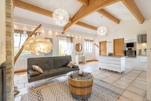 A modern living room with a sofa, a round wooden coffee table, and a unique light fixture.