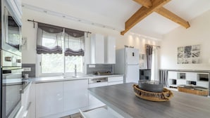 Una cocina moderna con armarios blancos, encimera de madera y horno empotrado.