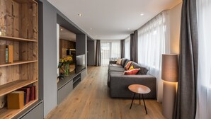 A modern living room with a grey sofa, a small round table, and a bookshelf.