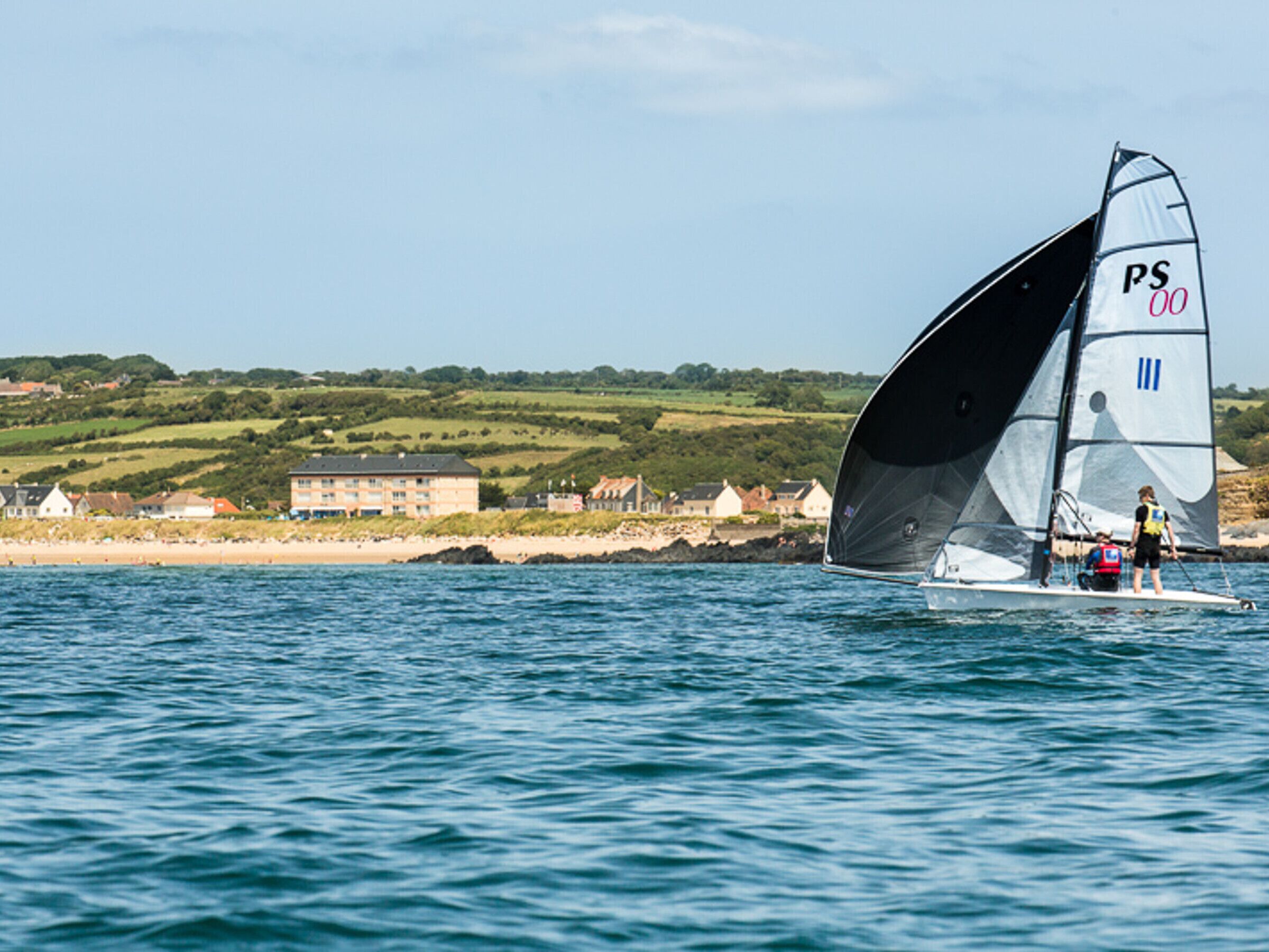 A sailboat with a PS 00 sail on a body of water.