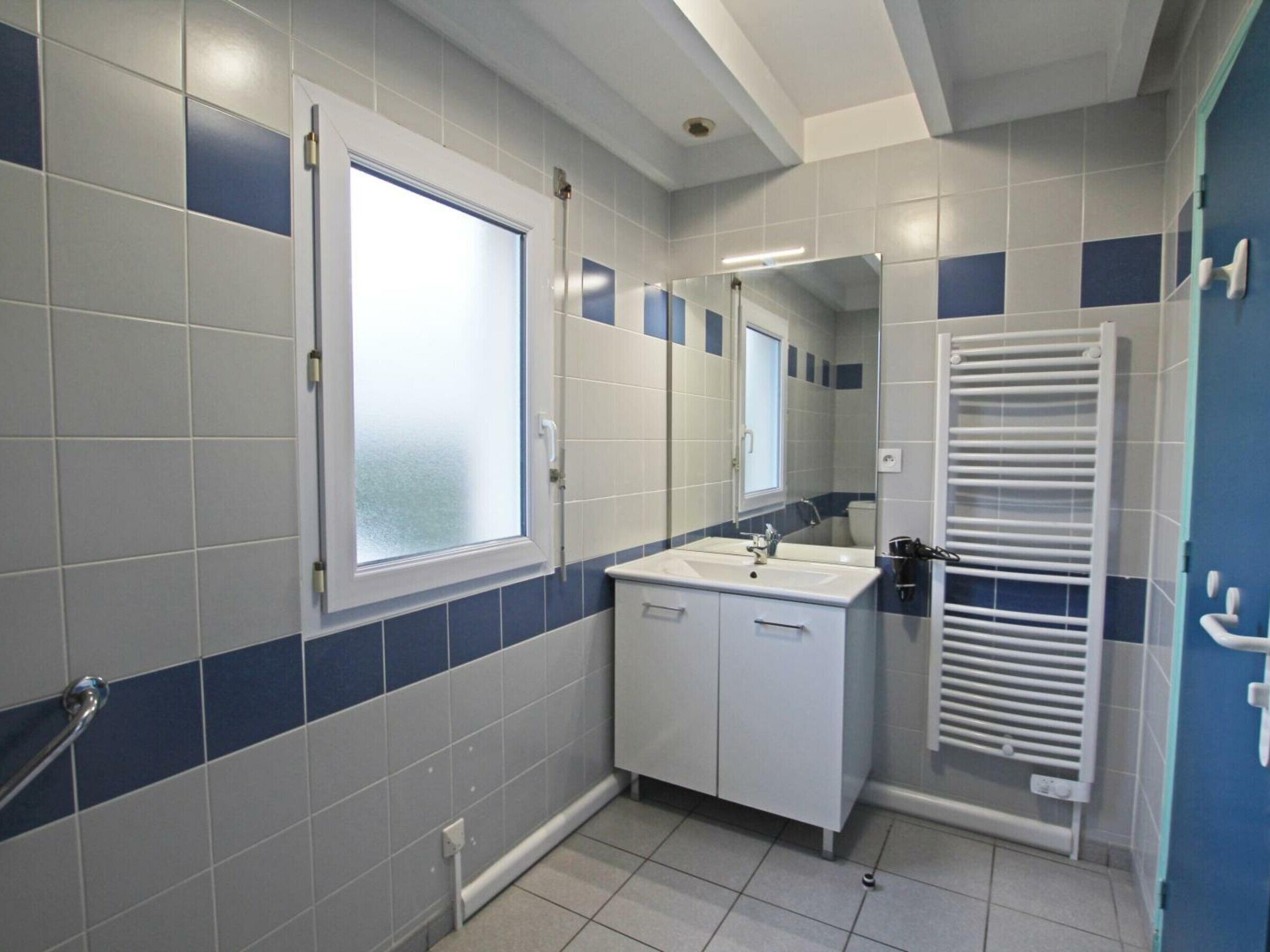 Een moderne badkamer met een wit wastafelmeubel, spiegel en witte kastjes.