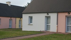 A row of single-story houses with a uniform architectural style, featuring a simple facade, a flat roof, and a small front yard. - Cozy cottage near the beach, wifi, pets allowed (Siouville-Hague)