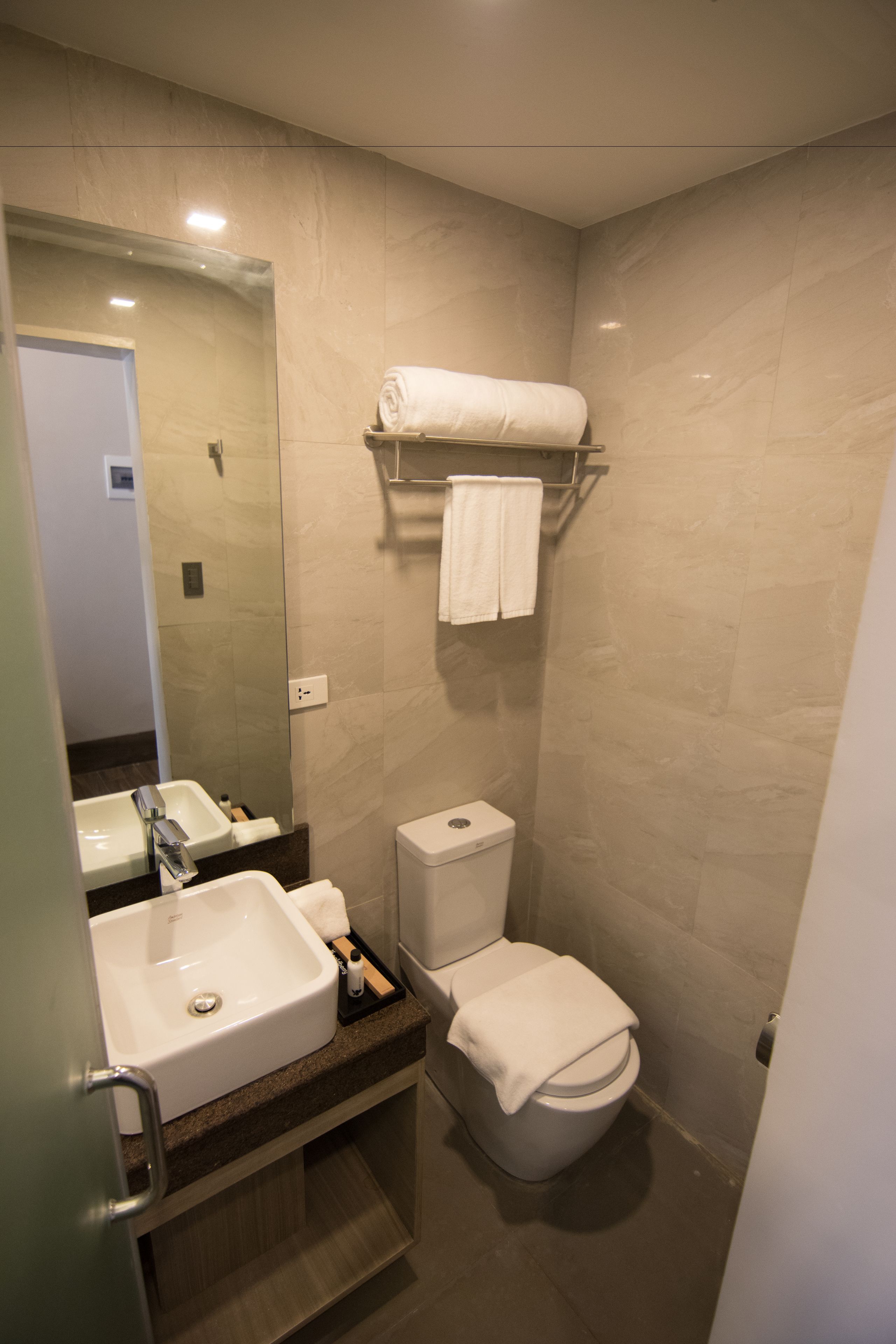 Een moderne badkamer met een wastafel, spiegel, toilet en handdoekhouder.