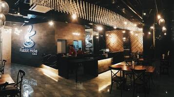 Een restaurant interieur met een modern design, bestaande uit een balie, een zitgedeelte en decoratieve verlichting.