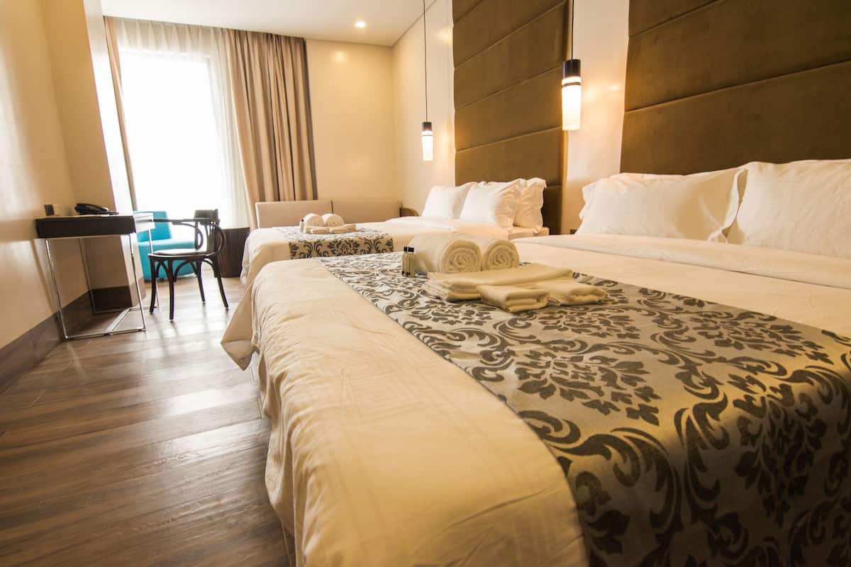 A hotel room with a large bed, a desk, and a chair.