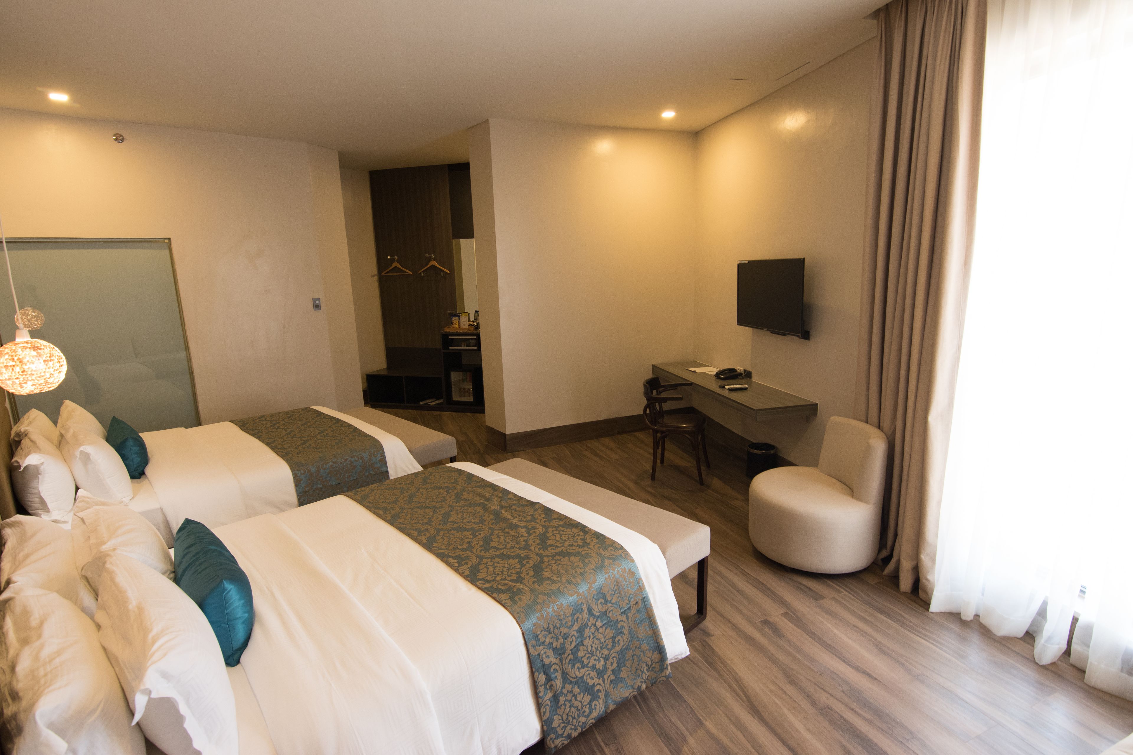 Habitación de hotel con dos camas, un escritorio, una silla y un televisor.
