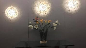 Una mesa de vidrio con un florero y tres lámparas fijadas a la pared.