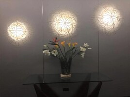 Una mesa de vidrio con un florero y tres lámparas fijadas a la pared.