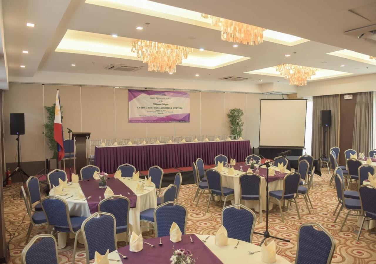 A conference room with round tables, chairs, and a stage with a podium.