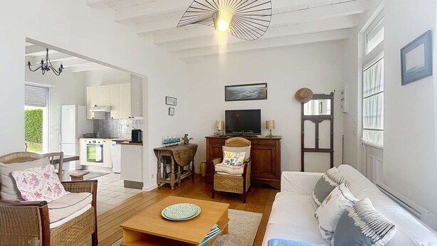 A spacious living room with a sofa, a coffee table, a television, and a dining area. - Charming Villa with Garden, Steps to Beach, Near Town, Free WiFi (Jullouville)