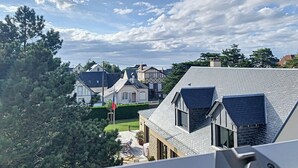 A residential area with houses, a flag, and a clear sky. - Charming Villa with Garden, Steps to Beach, Near Town, Free WiFi (Jullouville)