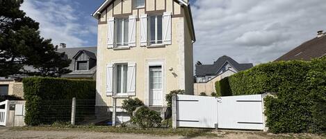 Een tweelaags huis met een hek, een zichtbare garage en een verzorgde haag.