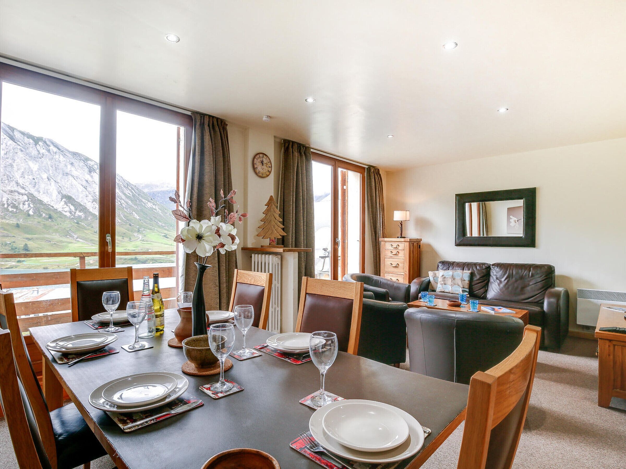 Un coin repas avec une table dressée pour quatre personnes, un canapé et une vue sur les montagnes.