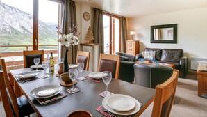 A dining area with a table set for four, a sofa, and a view of mountains.