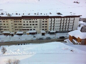 A multi-story hotel with a snow-covered roof and a parking area in front. - Tignes: 3-Room Apartment, 58m², 7 Pers, Mountain View (Tignes)