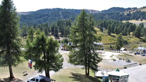 A campsite with a white pickup truck parked near a picnic table, surrounded by trees and a small building with a play area. - 3-room apartment for 6 with pool, pets allowed in Risoul 1850 (Risoul)