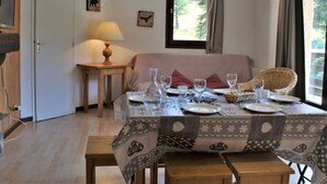A dining area with a table set for four, a sofa, a lamp, and framed animal silhouettes on the wall. - 3-room apartment for 6 with pool, pets allowed in Risoul 1850 (Risoul)