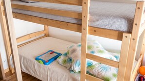 Un lit superposé avec un jouet bleu et un oreiller à motifs verts et blancs.