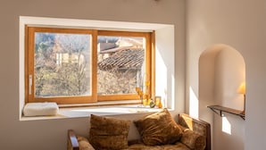 Une pièce chaleureuse avec une grande fenêtre, un banc rembourré et une lampe fixée au mur.